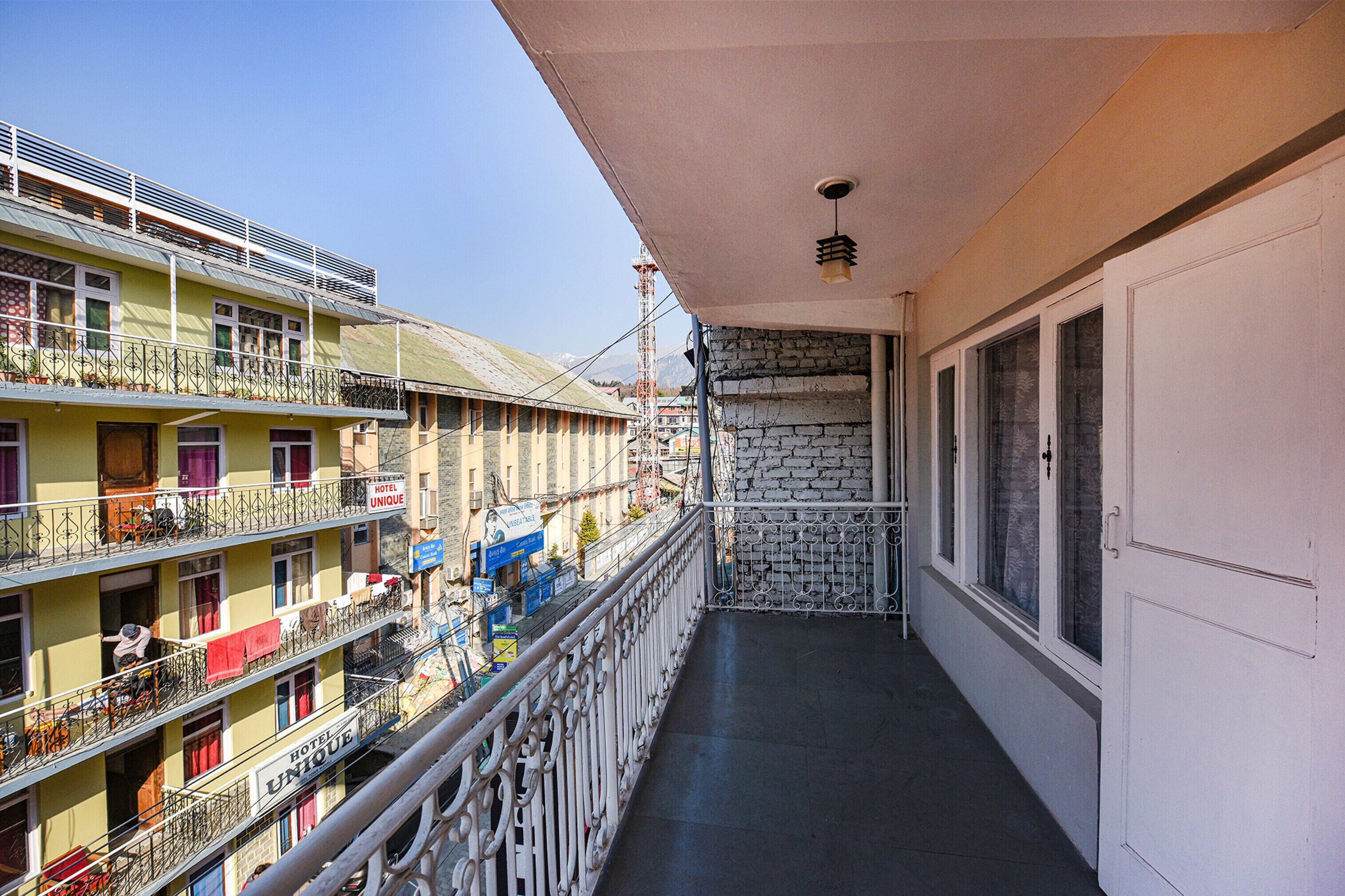 Ein mehrstöckiges Hotel mit Balkonen, einer Steinmauer und einer Tür.