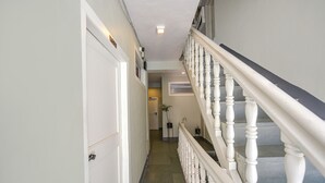 A hallway with a white door, a staircase with white balusters, and a potted plant. - Fabhotel Monalisa (Manali)