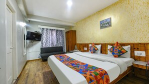 A hotel room with a large bed, a television, a wooden headboard, and a patterned wall. - Fabhotel Monalisa (Manali)