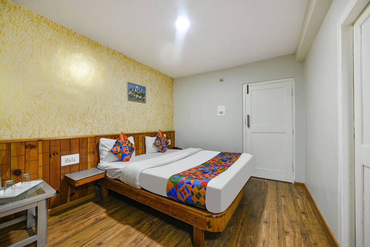 A bedroom with a wooden bed, white walls, and a wooden floor.