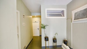 A narrow hallway with a door at the end, a small window, and two potted plants. - Fabhotel Monalisa (Manali)