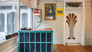 A reception desk with a sign indicating no washing clothes allowed, a framed artwork of the Mona Lisa, and a door with a unique design. - Fabhotel Monalisa (Manali)