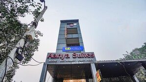 Un hotel chiamato 'Aanya Suites' con un cartello che indica la presenza di camere, un ristorante e una sala per feste.