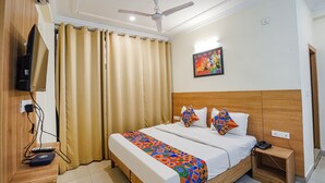 Una camera d'albergo con un letto, una TV, una ventola a soffitto e un quadro appeso al muro.