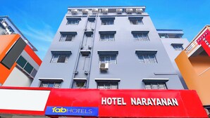 Un edificio de hotel de varios pisos con un llamativo letrero rojo que dice Hotel Narayanan.