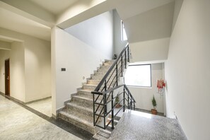 A modern interior with a marble staircase, a small potted plant, and a window providing natural light. - Fabhotel Naina Residency (Rishikesh)