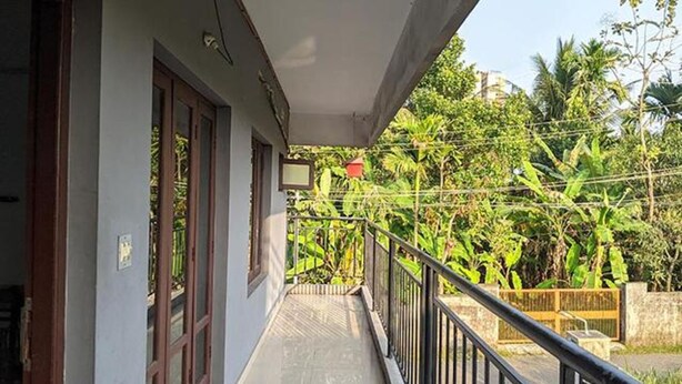 A balcony with a view of lush greenery and a red hanging sign. - Fabexpress Aabriz Residency (Kanayannur)