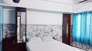 A hotel room with a bed, a wardrobe, a mirror, and a window with curtains. - Fabexpress Aabriz Residency (Kanayannur)