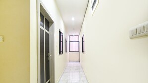 A corridor with a tiled floor, a door on the left, and a light switch on the right. - Fabexpress Blue Star (Ujjain)