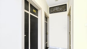 A hallway with a black door marked '202', a white door, and a small window with a metal grille. - Fabexpress Blue Star (Ujjain)