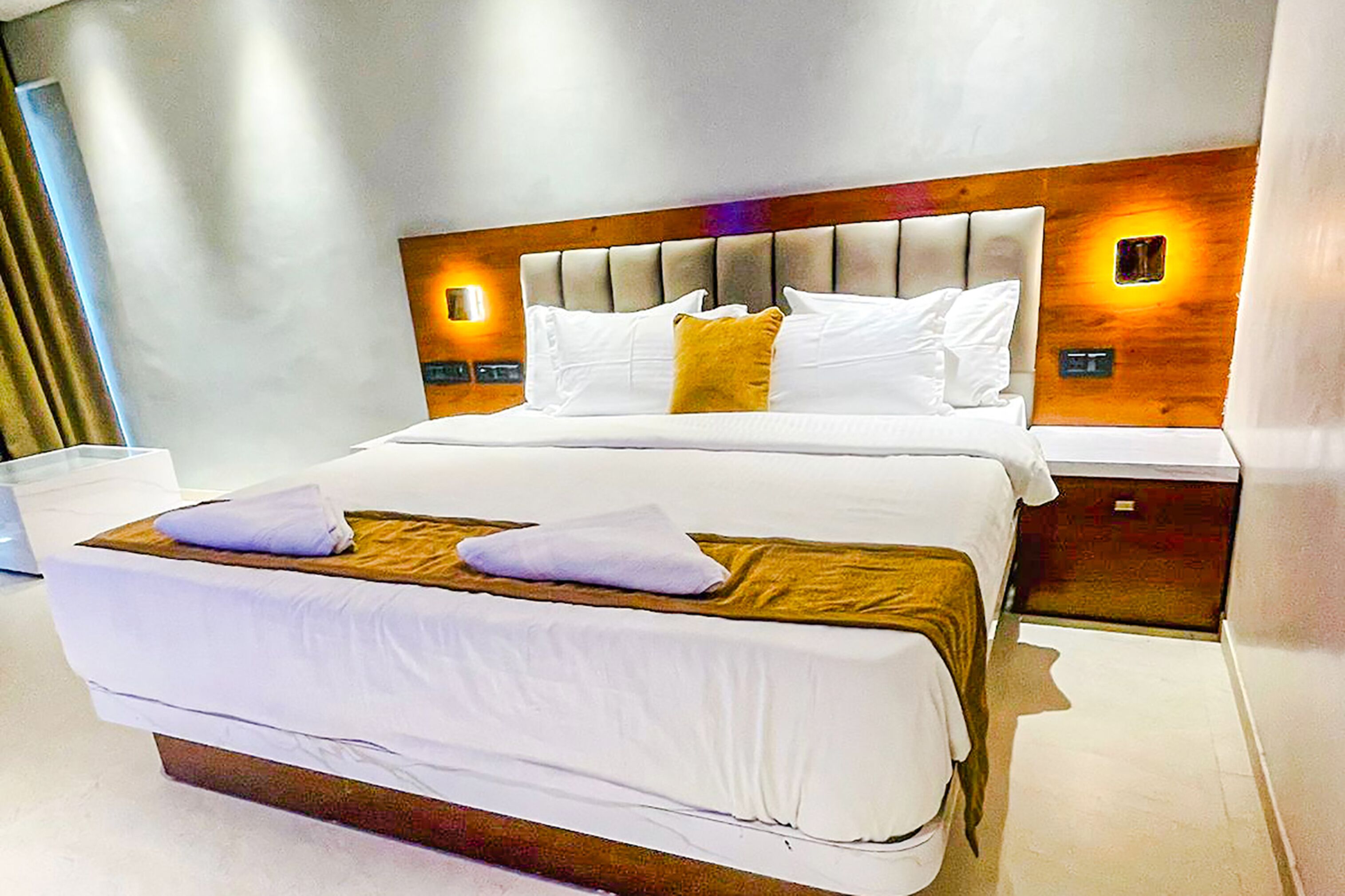 Een moderne hotelkamer met een groot bed, een houten hoofdeinde en twee nachtkastjes.