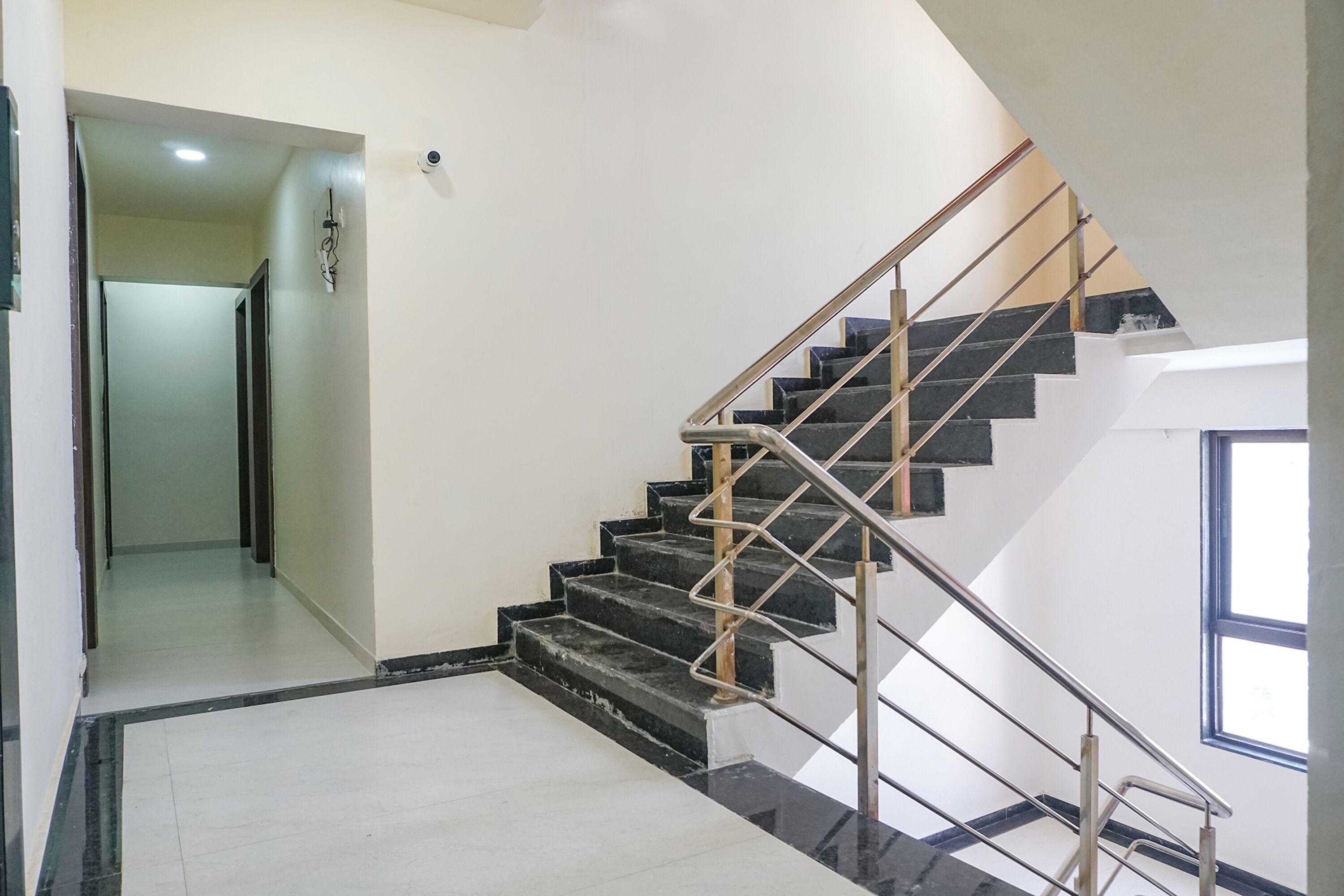 Una escalera con peldaños negros y barandillas de metal, que conduce a un piso superior.