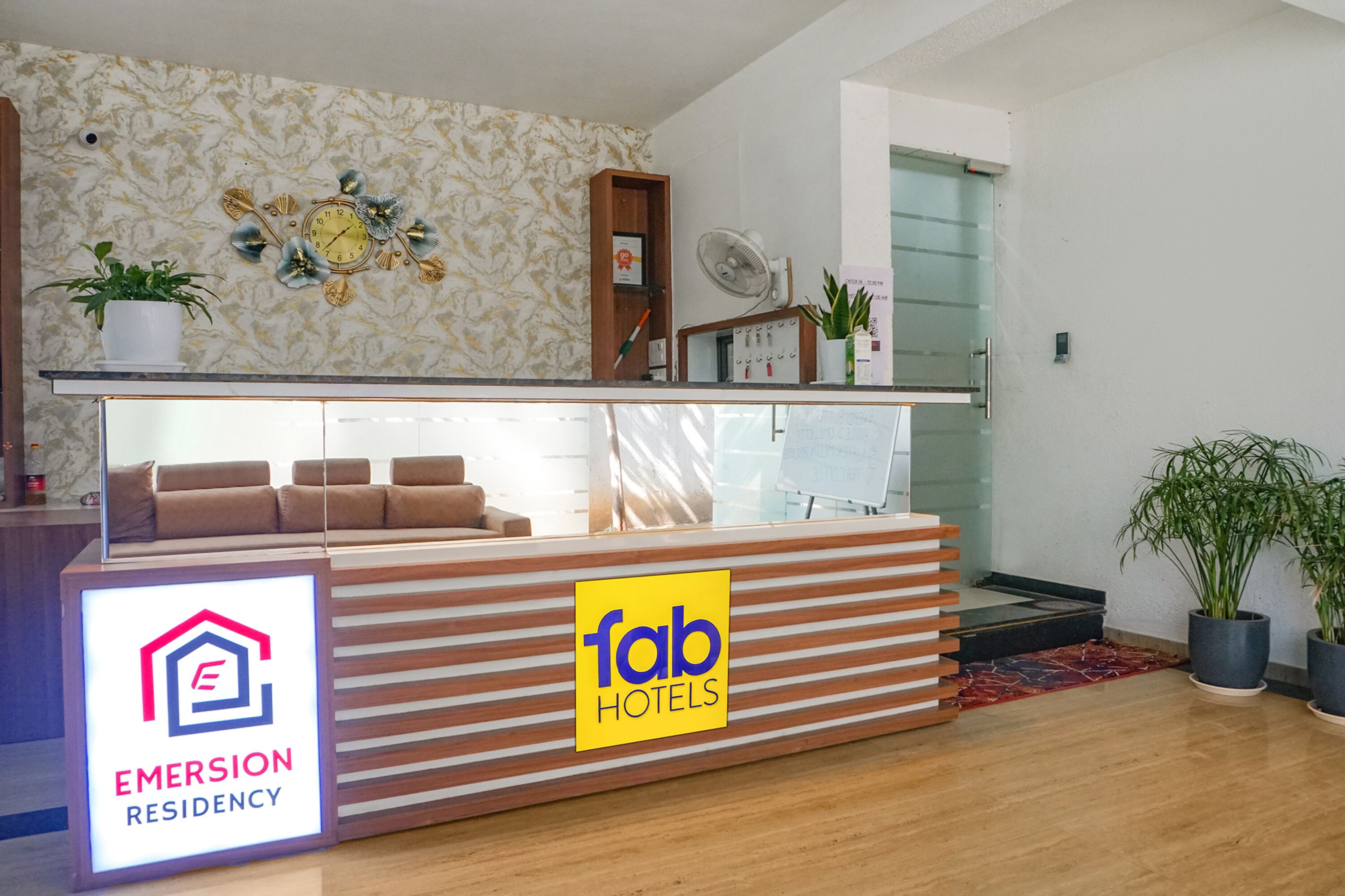Ein Hotel-Rezeptionsschalter mit einem Schild für 'Fab Hotels' und 'Emersion Residency'.