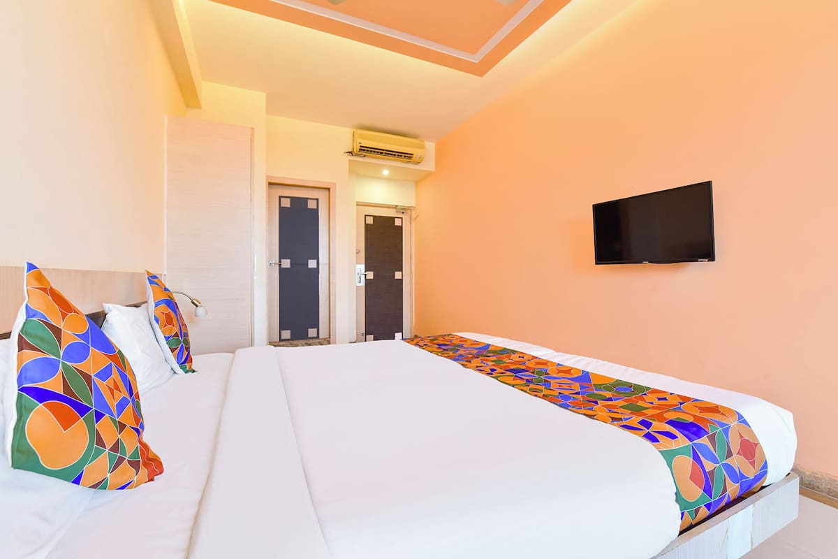 A hotel room with a large bed, a flat-screen TV, and two doors.