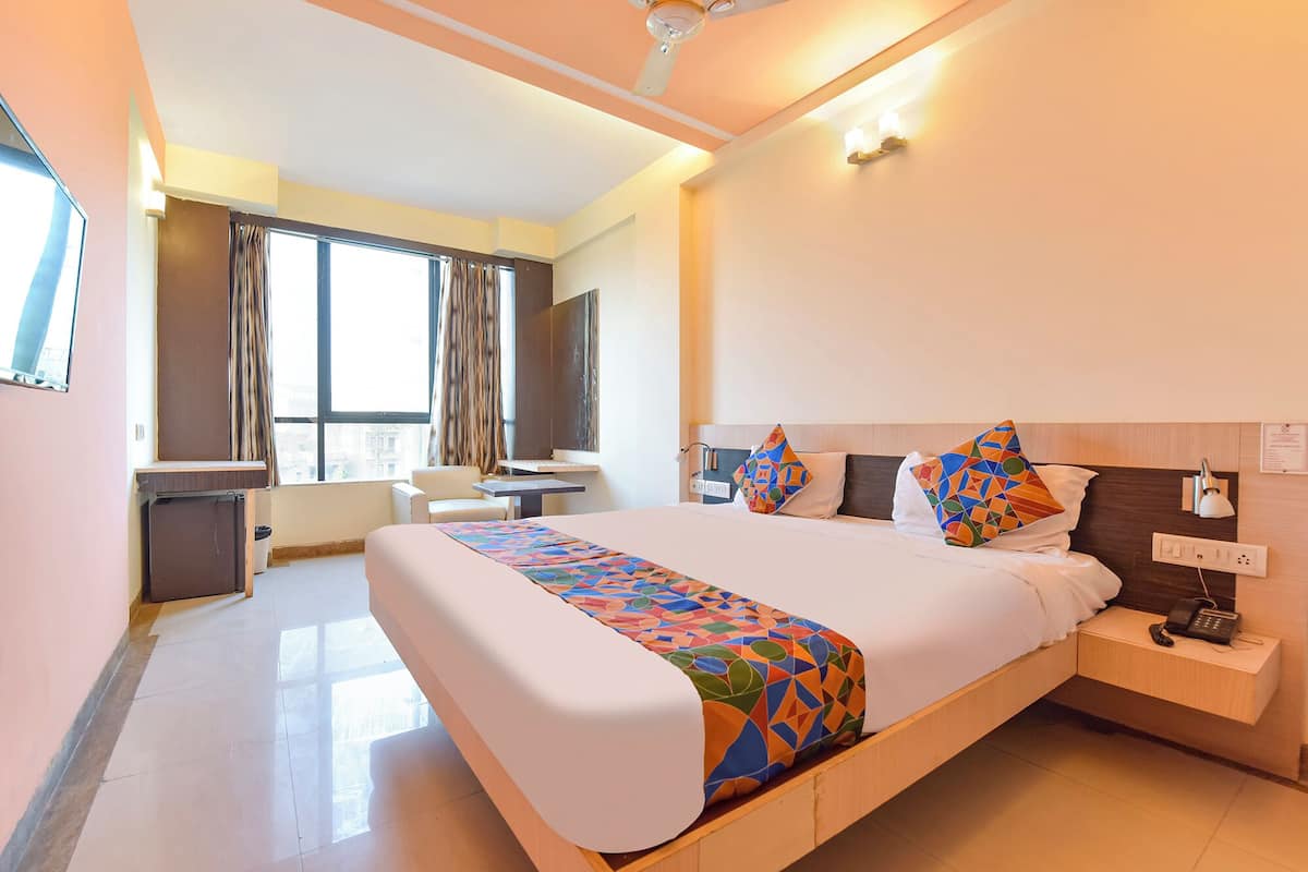 A hotel room with a large bed, a desk, and a chair.