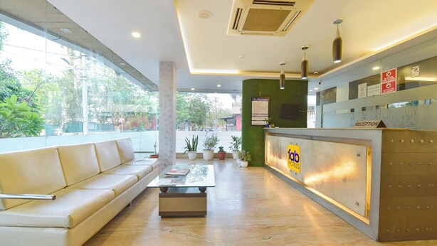 A hotel reception area with a sofa, reception desk, and potted plants. - FabHotel Apex Intercontinental - Nr. Pink Square Mall (Jaipur)
