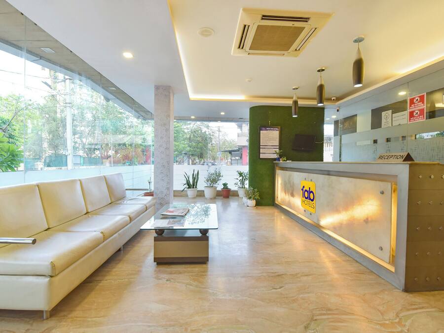 A hotel reception area with a sofa, reception desk, and potted plants.
