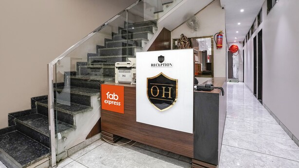 Zona de recepción de hotel con un mostrador, una escalera de cristal y un cartel que dice 'fab express'.