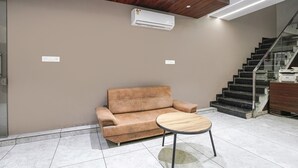 Un interior moderno con un sofá y una mesita, una escalera y un equipo de aire acondicionado.