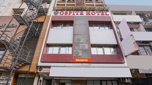 Fachada del Hotel Ospite con un cartel llamativo, una escalera de incendios y una entrada visible.