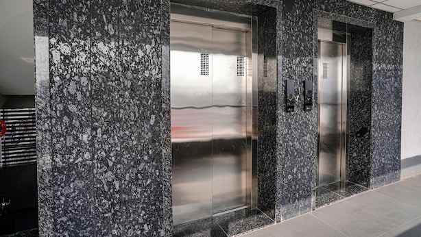 An elevator with a metallic finish and a control panel on the wall. - Fabhotel Sky City (Surat)