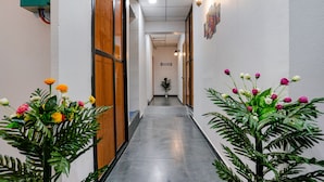 A hallway with a potted plant and flowers on either side, leading to a door at the end. - Fabhotel Sky City (Surat)