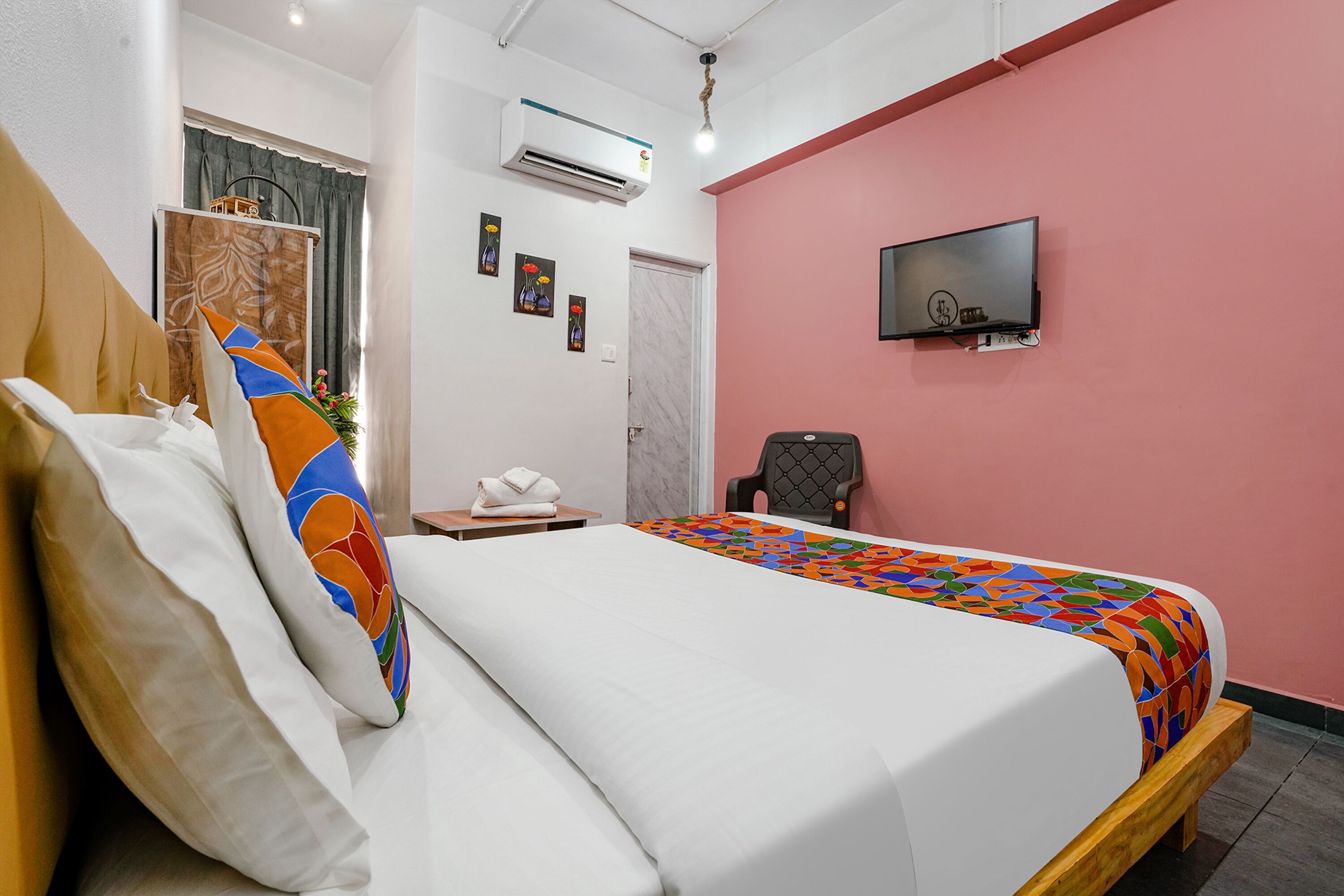 A hotel room with a bed, a TV mounted on the wall, and a window with curtains.