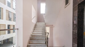 A narrow stairway with a handrail, leading to a landing with a door and a window. - Fabhotel Perams Grand Inn (Hyderabad)
