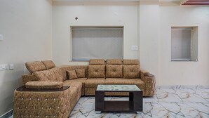 A modern living room with a sectional sofa, a coffee table, and a patterned floor. - Fabhotel Perams Grand Inn (Hyderabad)