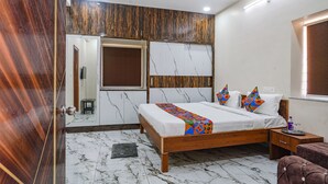 A bedroom with a wooden bed, a ceiling fan, a marble floor, and a wooden wardrobe. - Fabhotel Perams Grand Inn (Hyderabad)