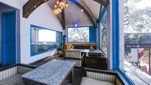 Un restaurante con una decoración rústica, que presenta vigas de madera, una mesa de piedra y asientos acolchados a rayas.