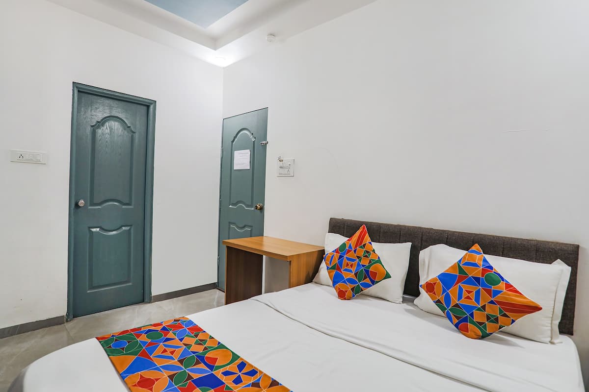 A room with a bed, two doors, a nightstand, and a patterned bedspread.