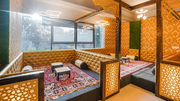 Une pièce avec une grande fenêtre, un canapé, une petite table et un tapis à motifs.