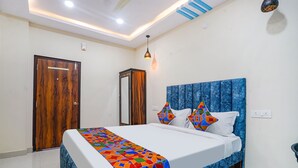 Une chambre à coucher avec un lit, une porte en bois, une armoire et une tête de lit bleue.