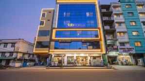 Un hôtel moderne, reconnaissable à son panneau « fab hotels » bien visible, qui s’étend sur plusieurs étages et dispose d’un espace commercial au niveau du rez-de-chaussée.