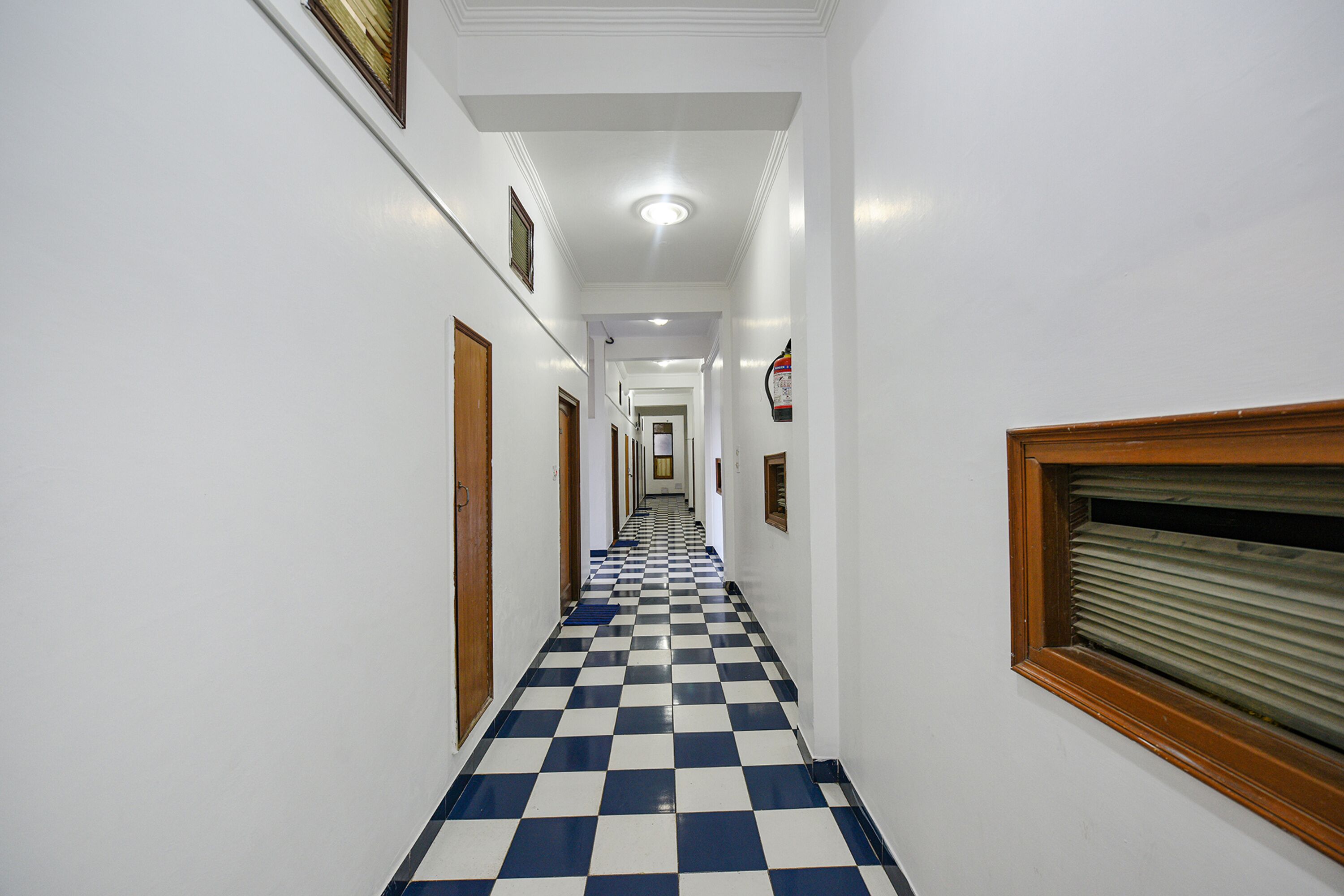 Ein Hotelkorridor mit Schachbrettboden, weißen Wänden und Holztüren.