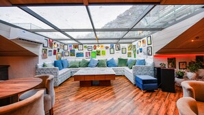 Un interior moderno con techo de madera, techo de cristal y zona de estar con sofá y reposapiés.
