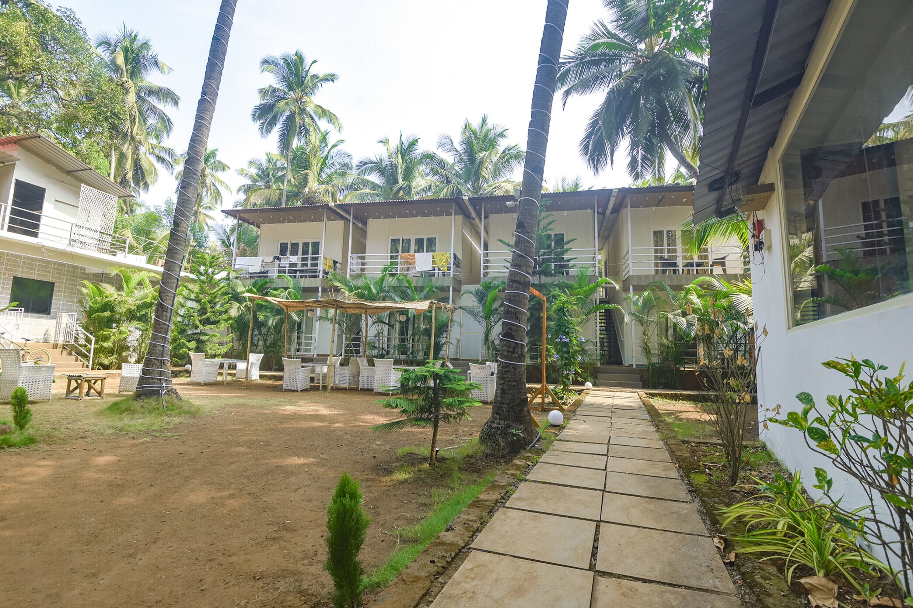 A courtyard with a paved walkway, palm trees, and outdoor furniture.