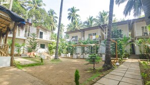 A courtyard with a dirt ground, palm trees, and a paved walkway. - Fabhotel La Volga (Morjim)