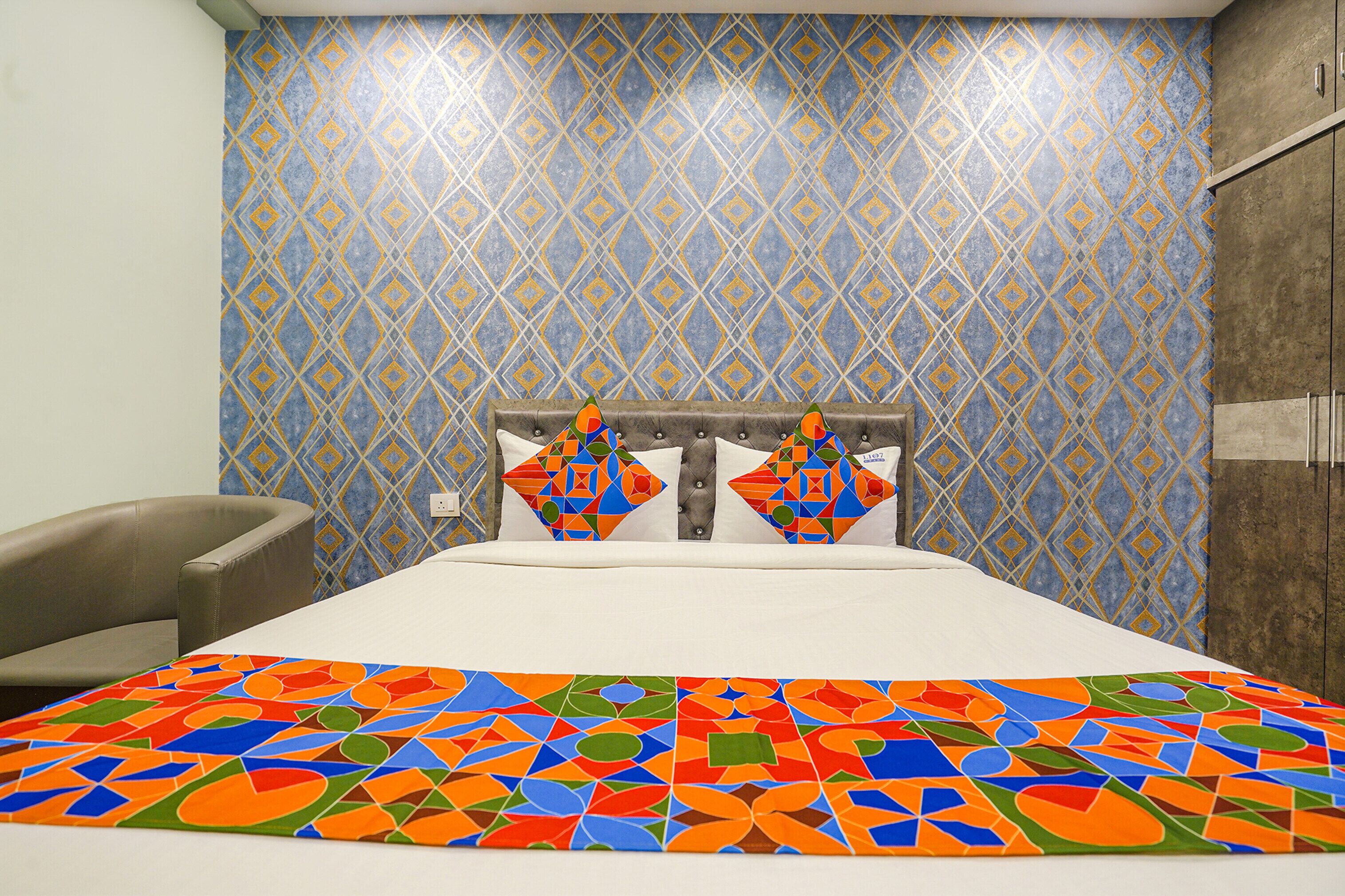 Una stanza con un letto, una sedia e una parete decorata.