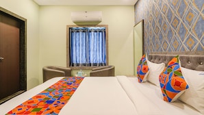 A hotel room with a bed, a desk, a chair, a window with curtains, and a patterned wall. - Fabhotel Lio7 Grand (Hyderabad)