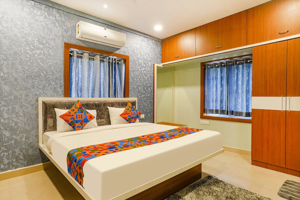 Quarto moderno com cama grande, guarda-roupa de madeira e janela com cortinas.