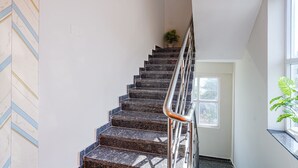 A staircase with a metal handrail, a potted plant at the top, and a window on the right side. - Fabhotel Lio7 Grand (Hyderabad)