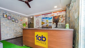 A reception area with a wooden counter, a 'fab hotels' logo, and a 'Symphony Suites' sign. - Fabexpress Symphony Suites (Bengaluru)