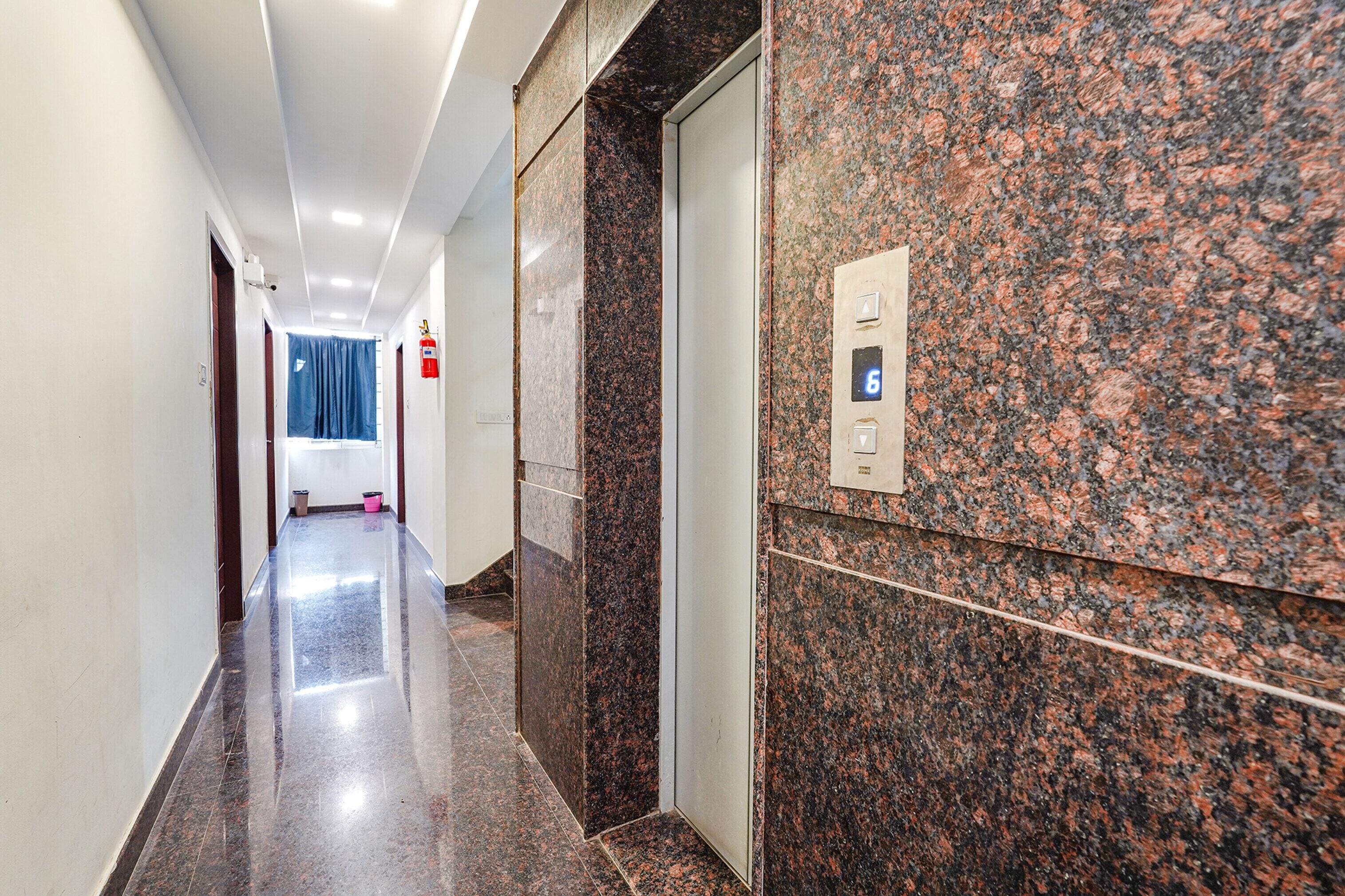 A modern hallway with a marble wall, a fire extinguisher, and a door with a number 6 sign.