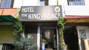 The entrance to Hotel The King Palace with a sign above the door, a potted plant in the center, and a staircase leading up to the entrance. - FabHotel The King Palace (Indore)