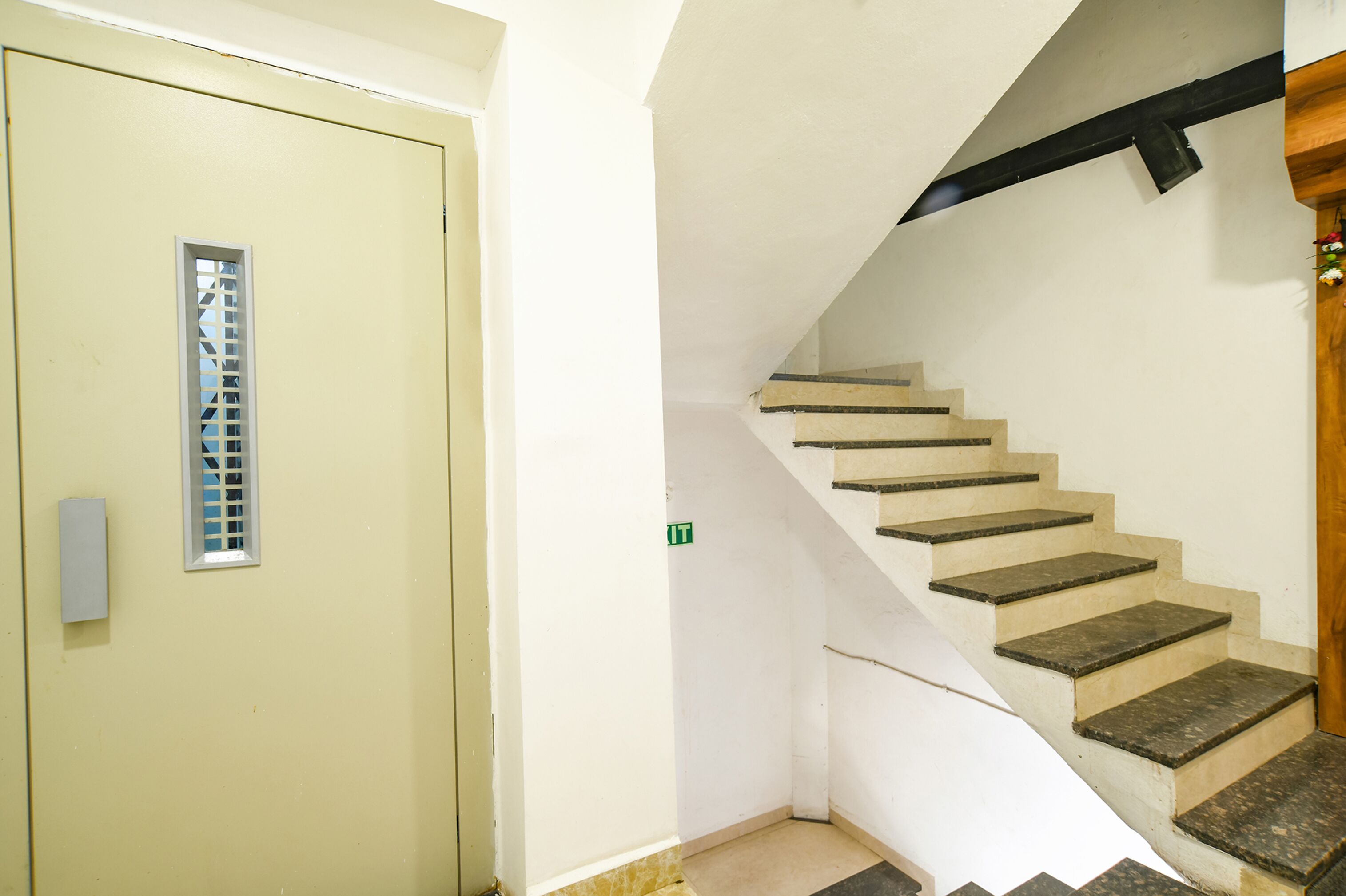 A staircase with a handrail and a door with a vent.