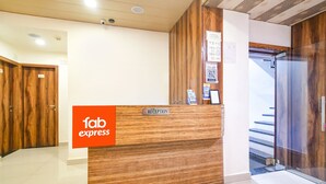 A reception desk with a wooden finish and a sign that reads "fab express." There are doors with numbers on them and a glass door leading to a staircase. - FabHotel The King Palace (Indore)