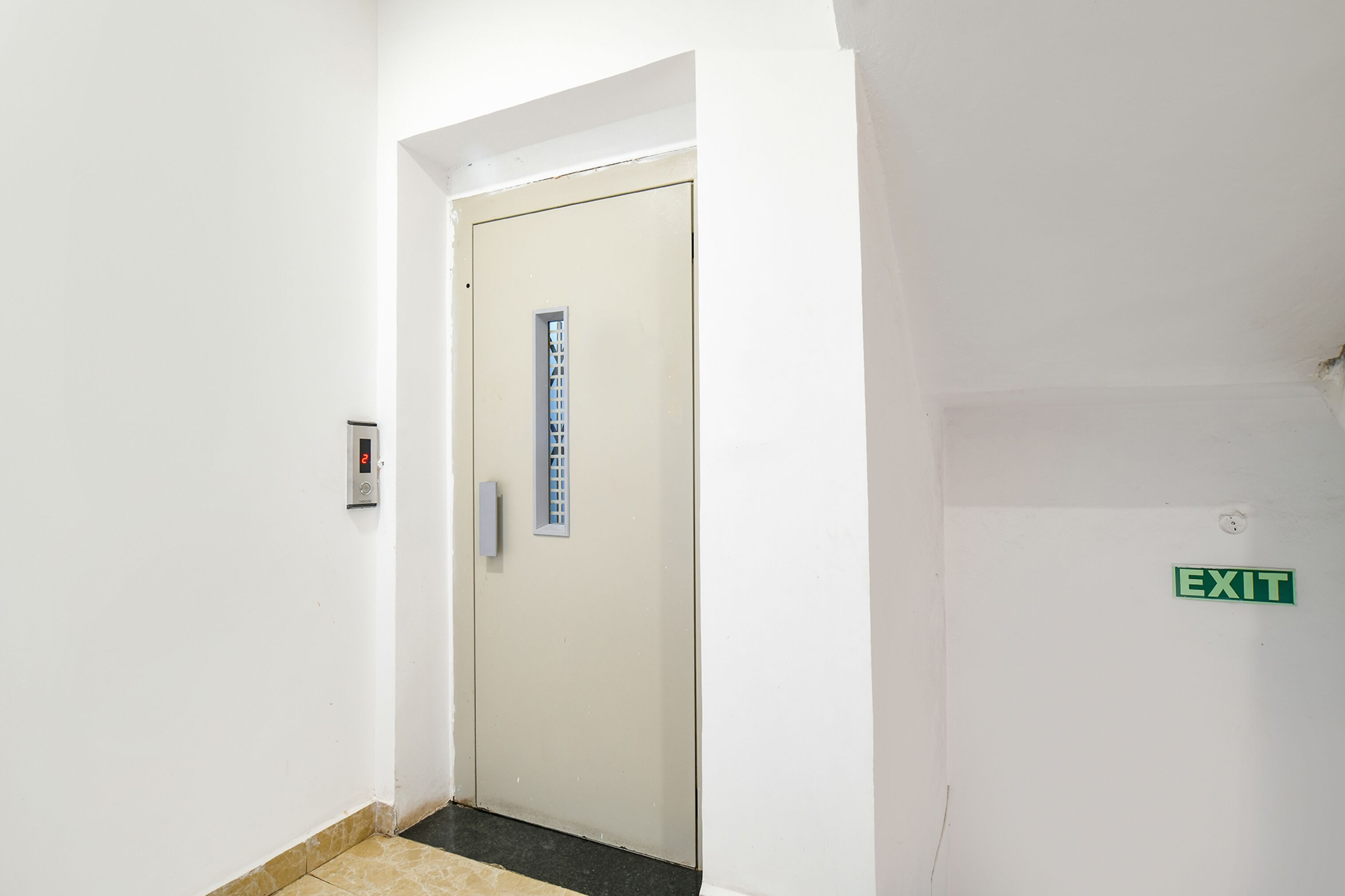 A white door with a small window, an elevator control panel, and an EXIT sign.