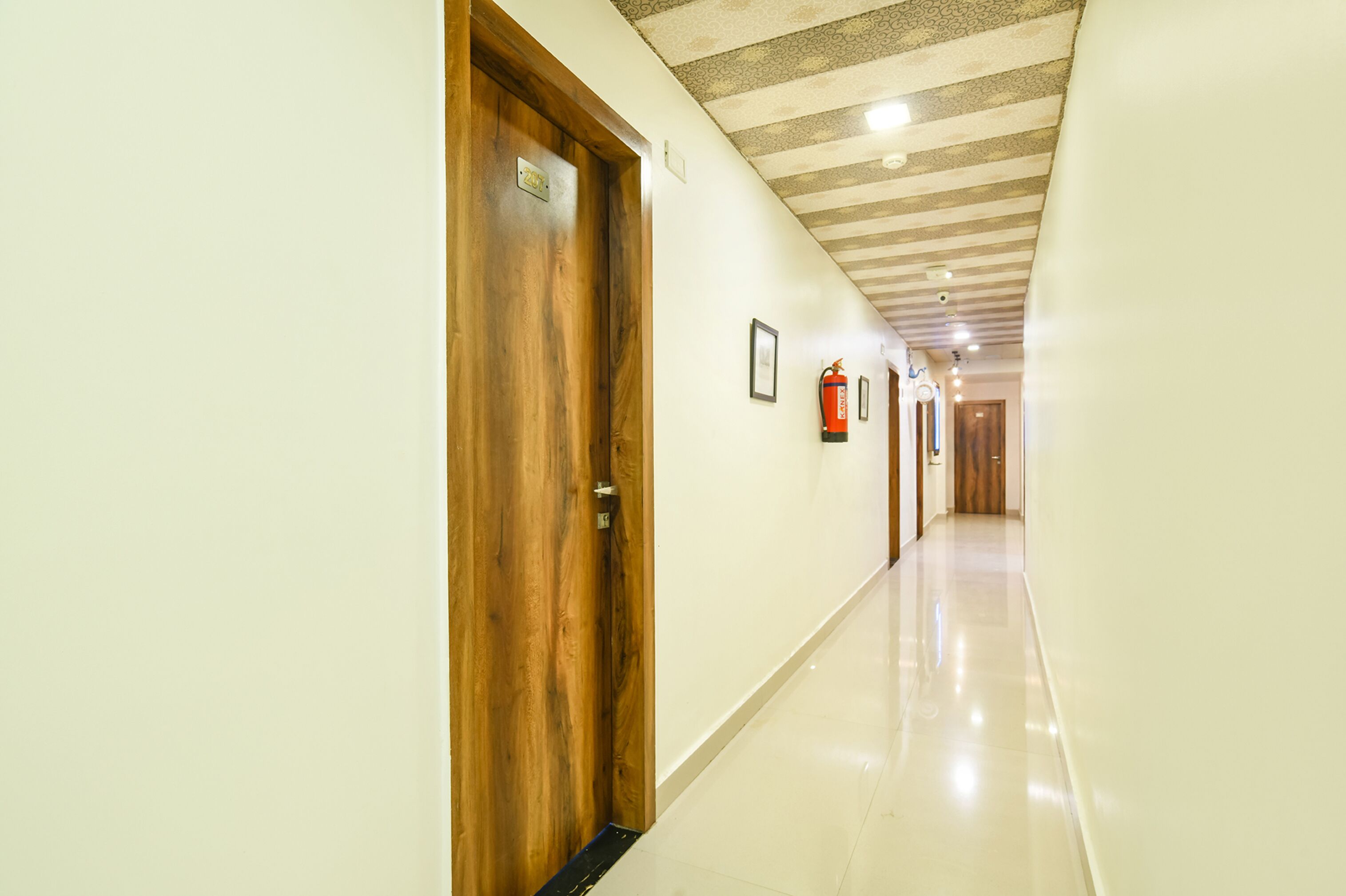 A long, well-lit hallway with wooden doors and a tiled floor.